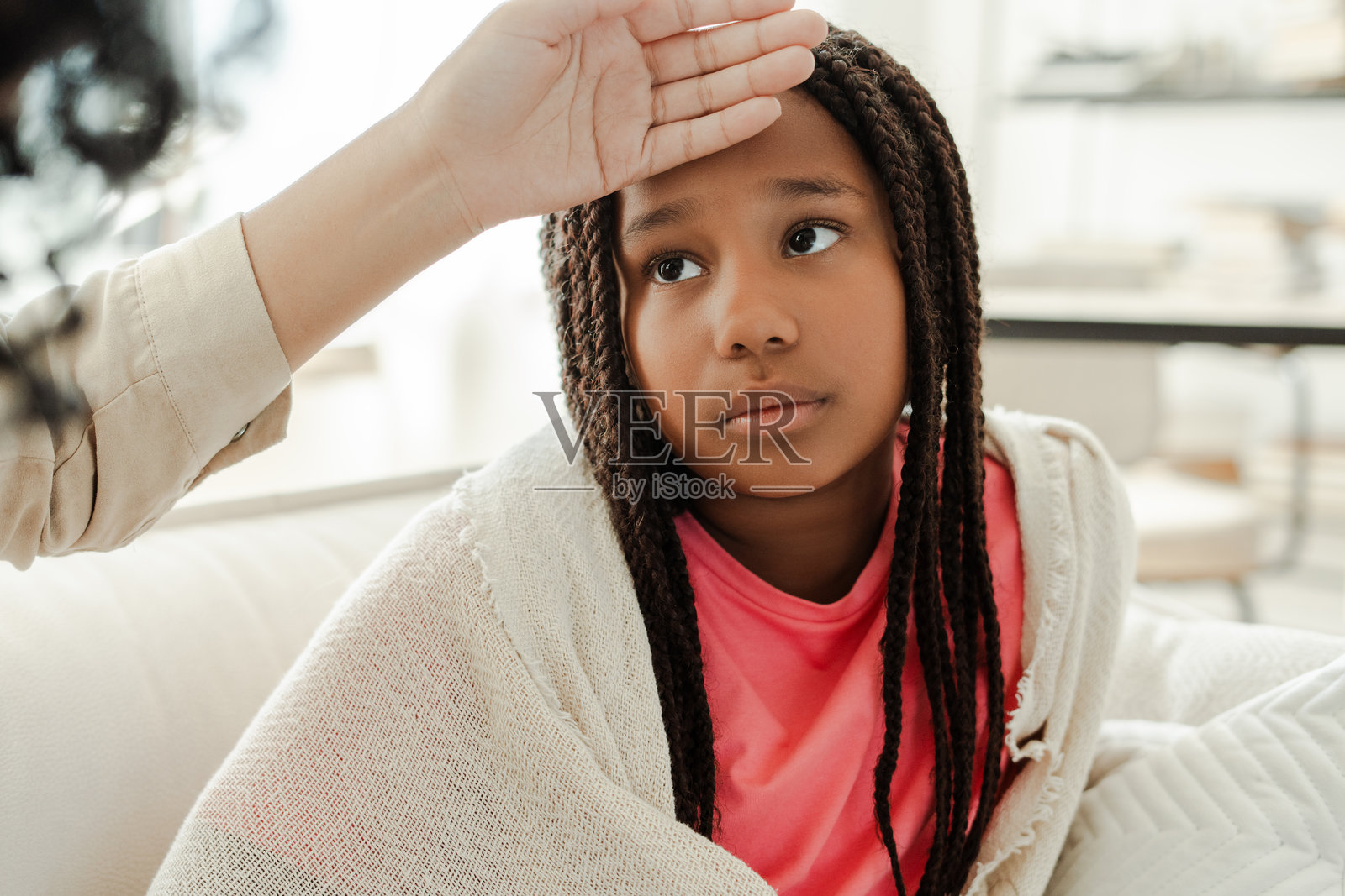 医生在家中检查躺在沙发上的生病女孩的体温照片摄影图片
