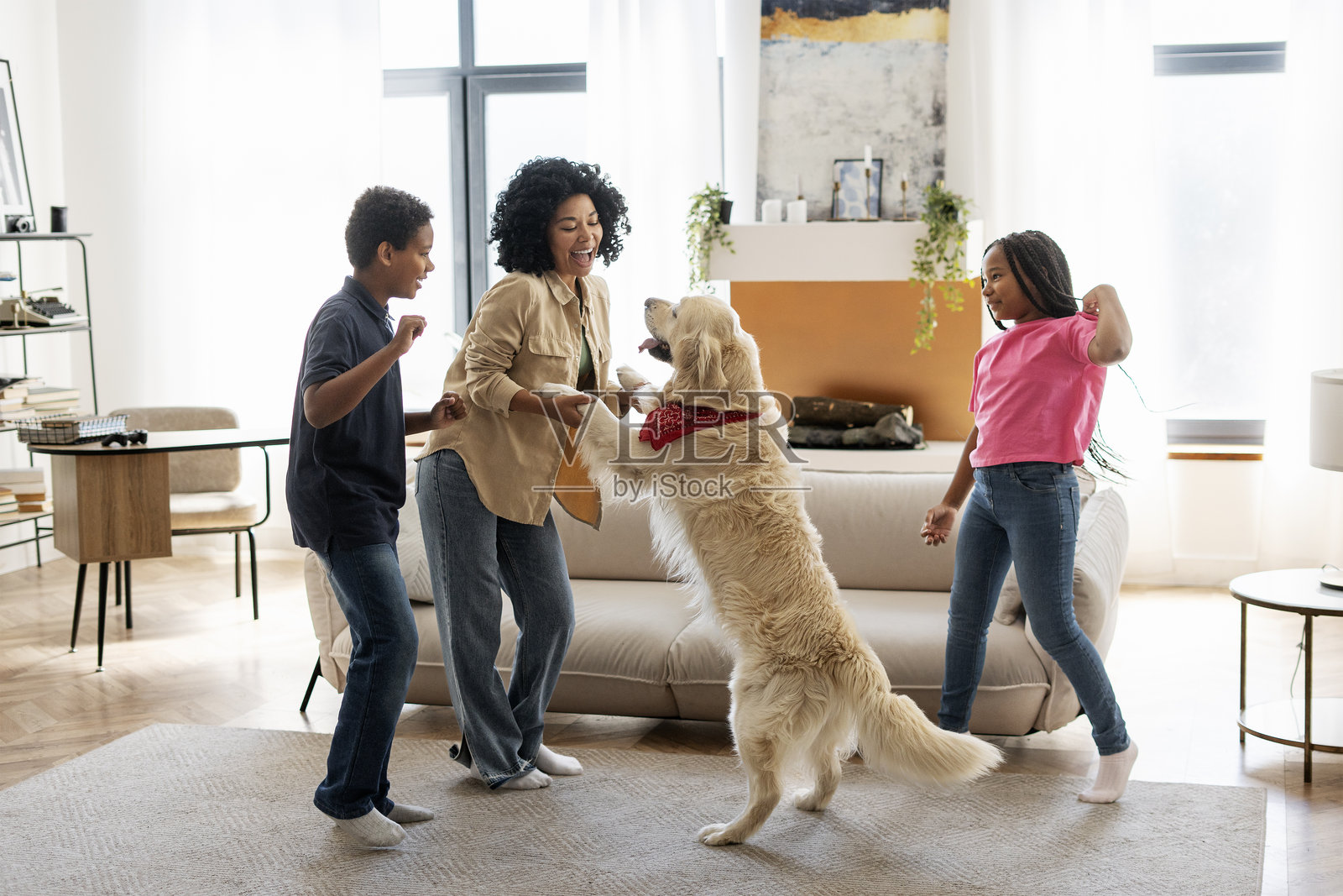 快乐的家庭在客厅里与他们的狗一起跳舞照片摄影图片