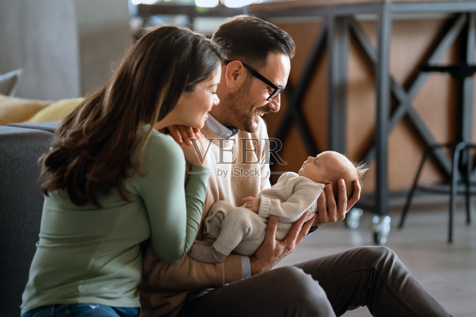 微笑的父母在家中抱着他们的新生女儿照片摄影图片