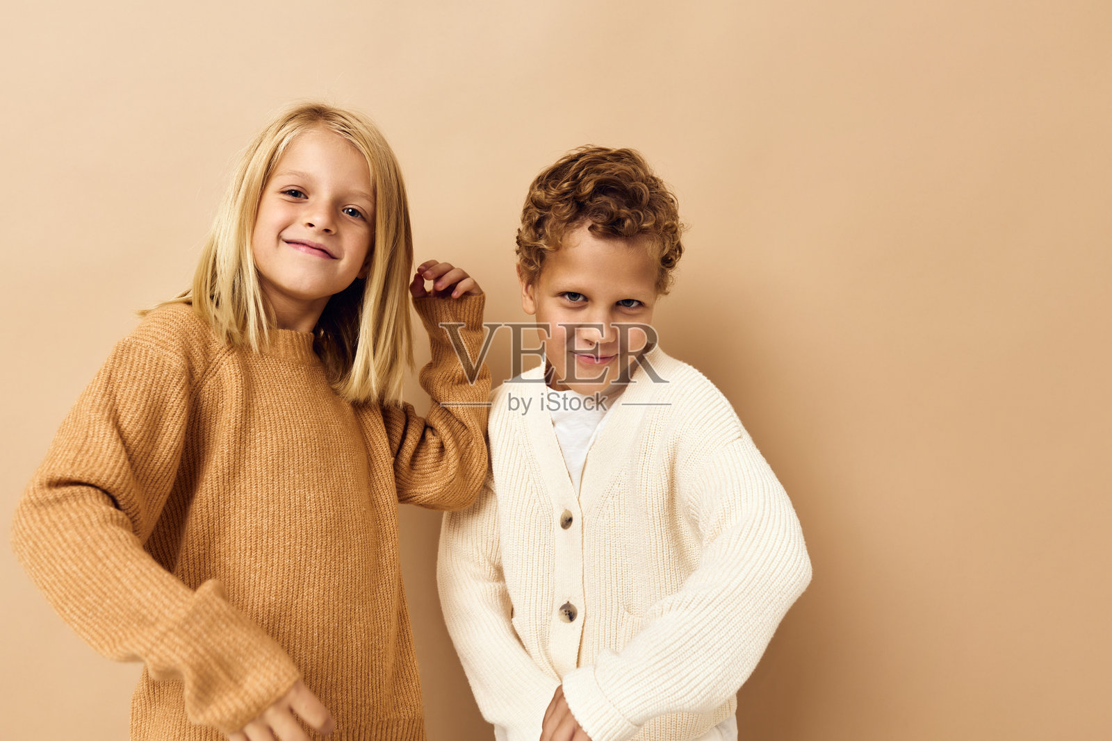 穿着毛衣的小女孩和小男孩，背景为单色。照片摄影图片