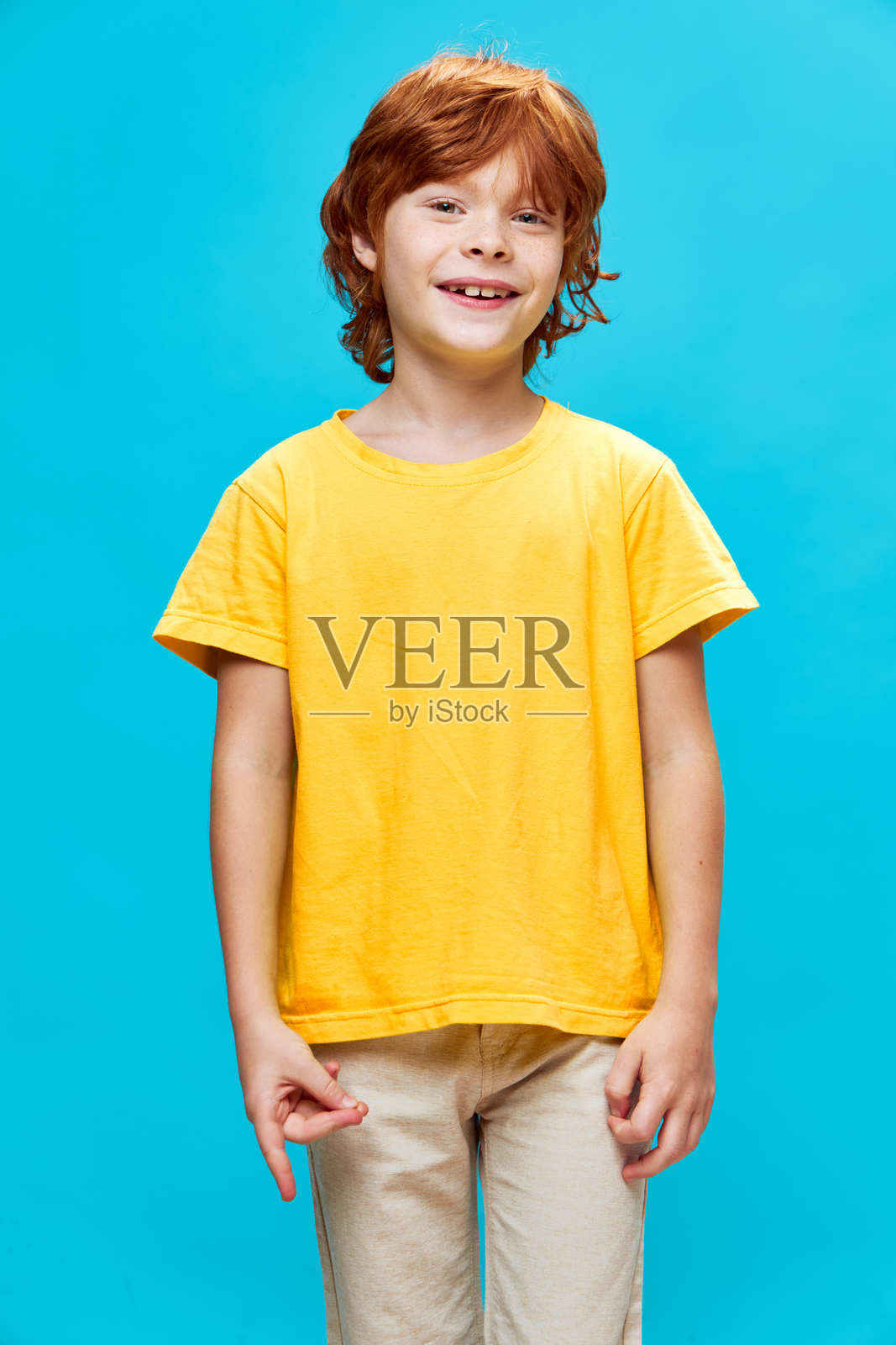 快乐的红发孩子穿着黄色T恤，食指和拇指相连。照片摄影图片