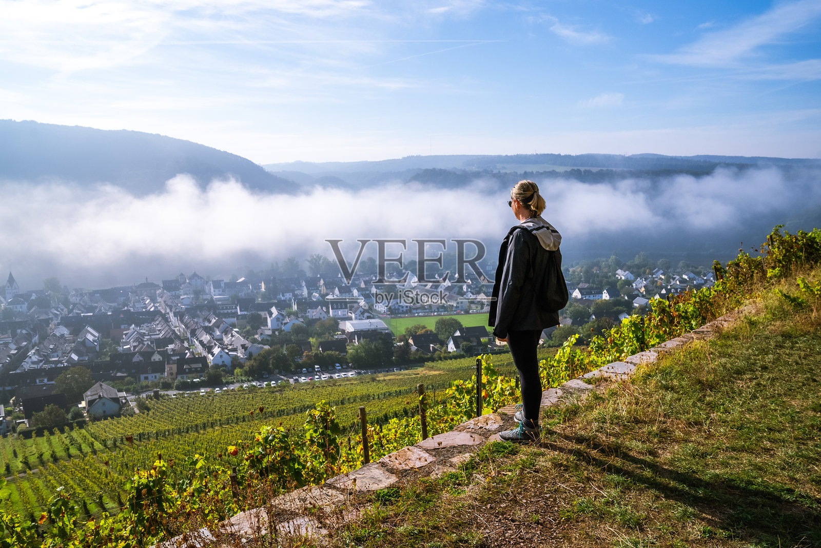 女性徒步旅行者在德国温宁根的小镇上欣赏日出美景，背景是莱茵河谷的葡萄园。照片摄影图片