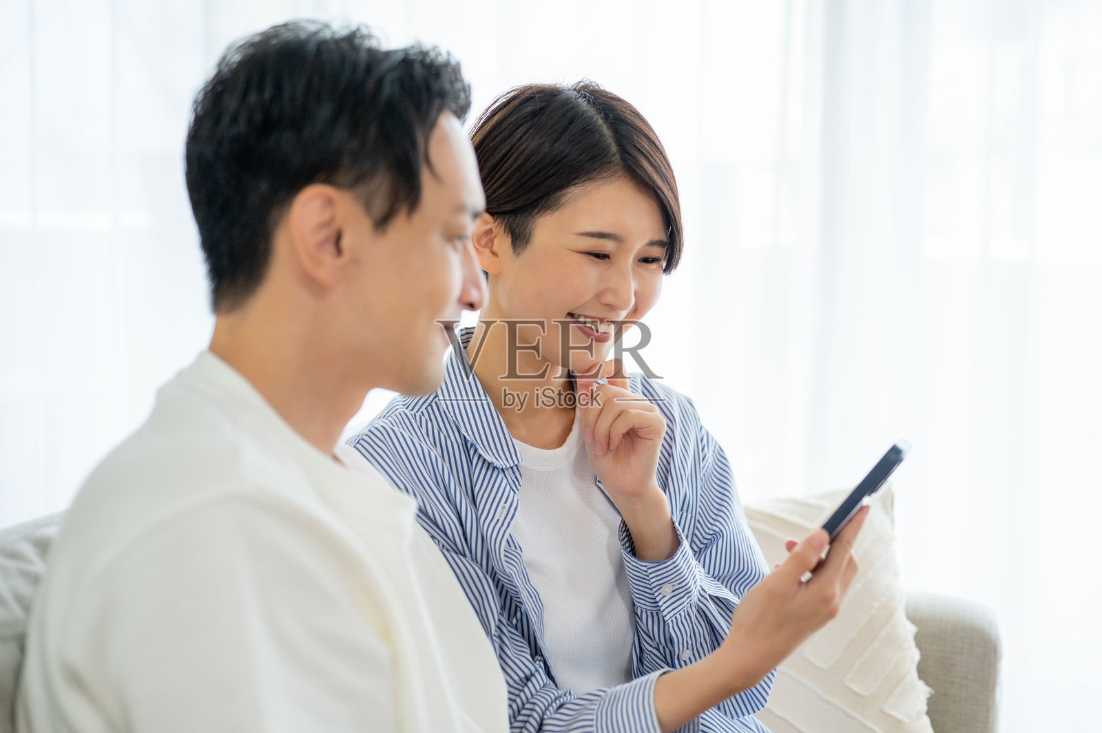男女在客厅里看智能手机照片摄影图片