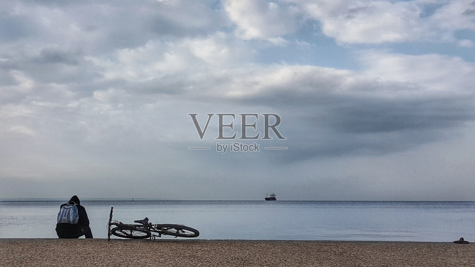 背影男子坐在自行车旁，面朝大海照片摄影图片