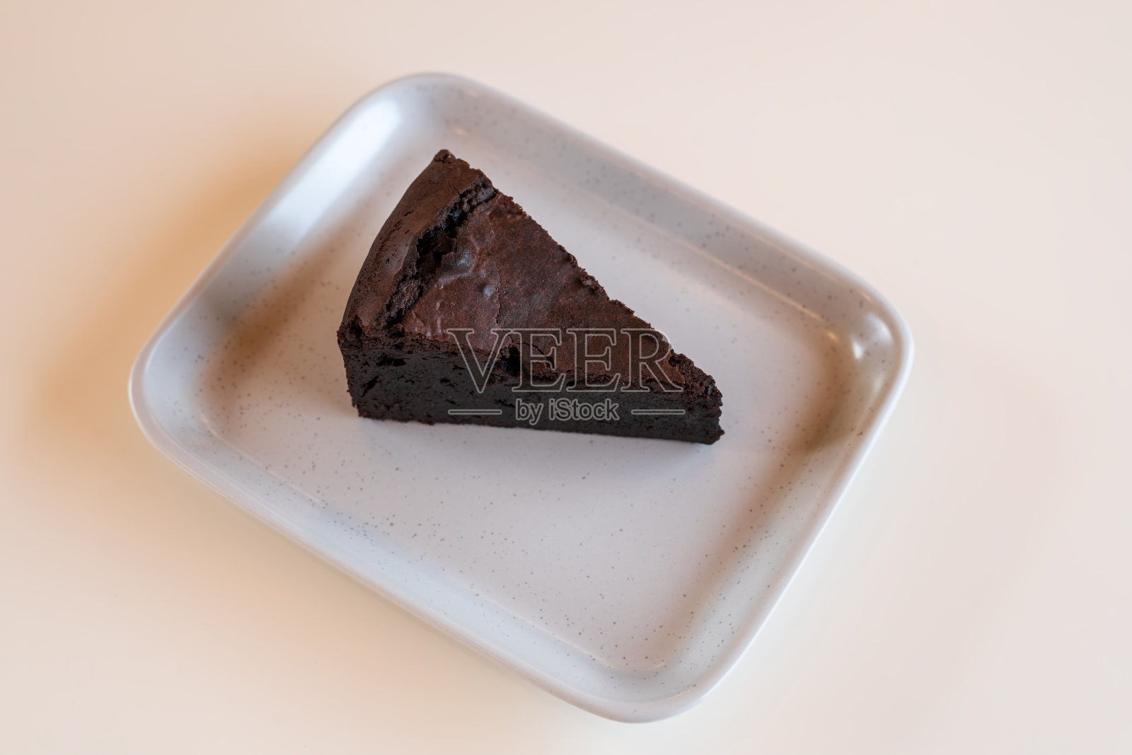 一堆巧克力布朗尼放在白色盘子上，看起来令人垂涎，是自制的烘焙甜点。照片摄影图片