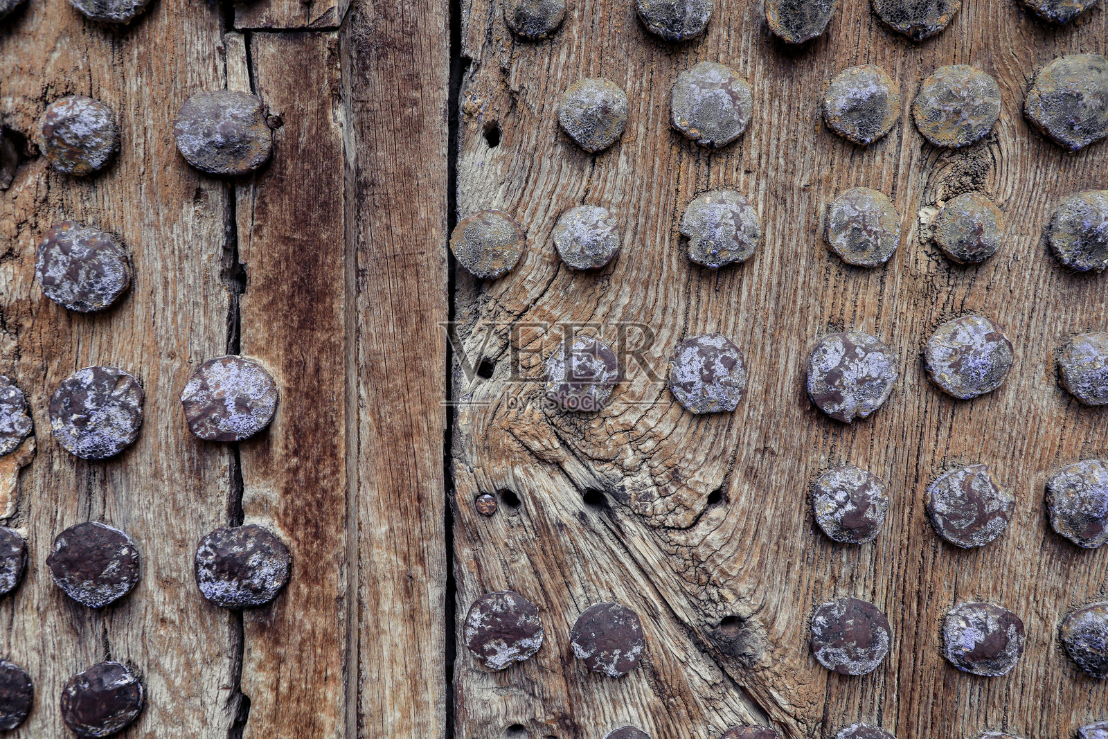 古老建筑中装饰着大型风化铁钉的乡村木门，展示了历久弥新的工艺。照片摄影图片