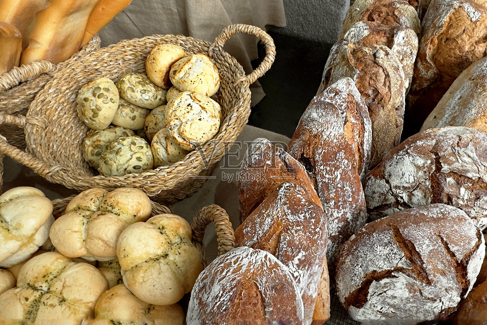 展示柜中陈列着各式各样的面包和小圆面包，出售新鲜的糕点。照片摄影图片