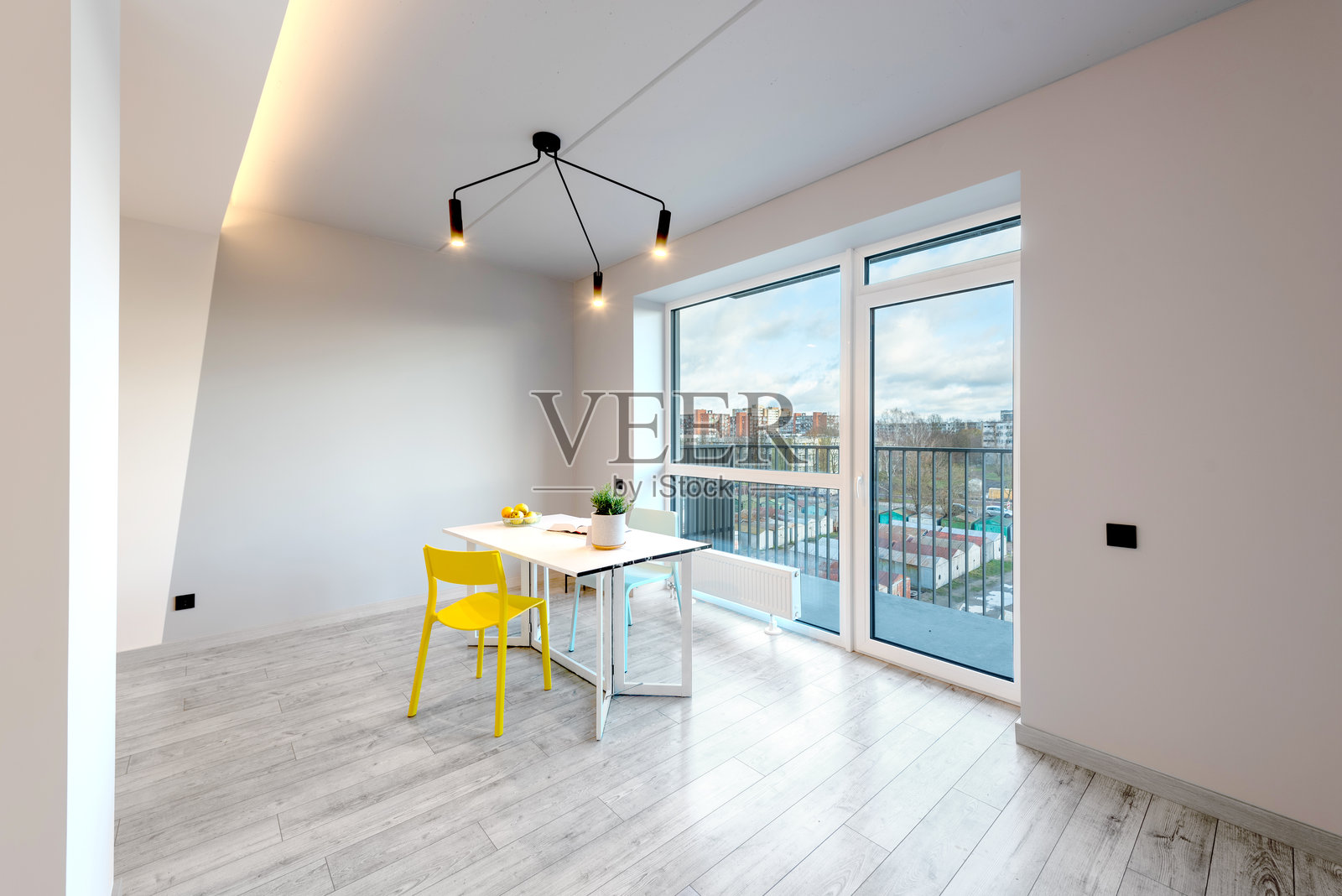 家居室内。厨房与开放式客厅餐厅。桌子上的书籍，苹果和五彩斑斓的椅子。窗户和白天的景色。照片摄影图片