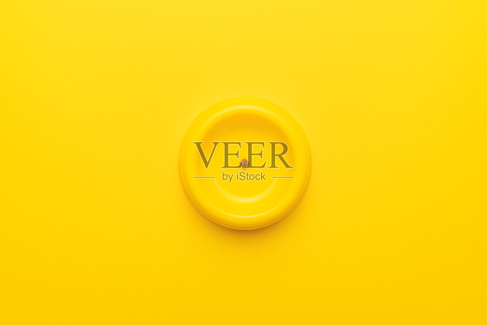 黄色宠物碗上有干粮残留，背景为黄色照片摄影图片