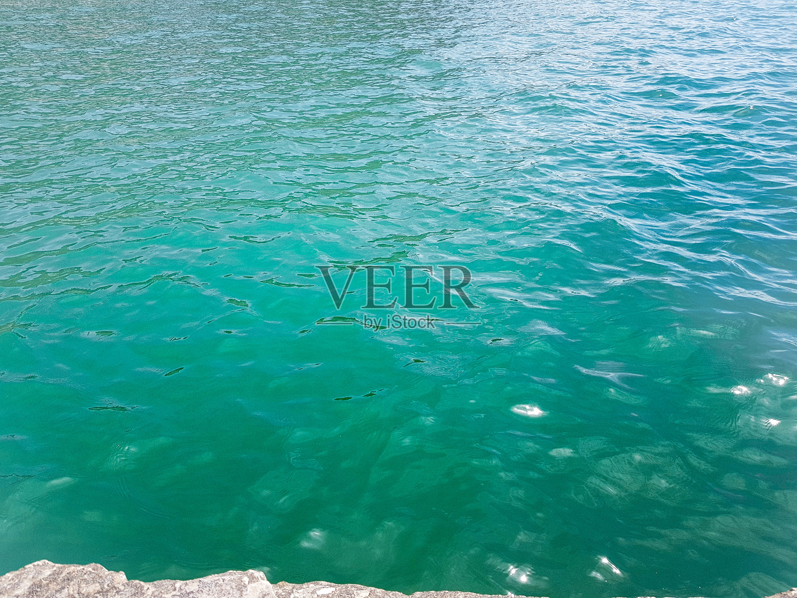 宁静海洋的背景，碧绿清澈的水面和阳光照耀。照片摄影图片