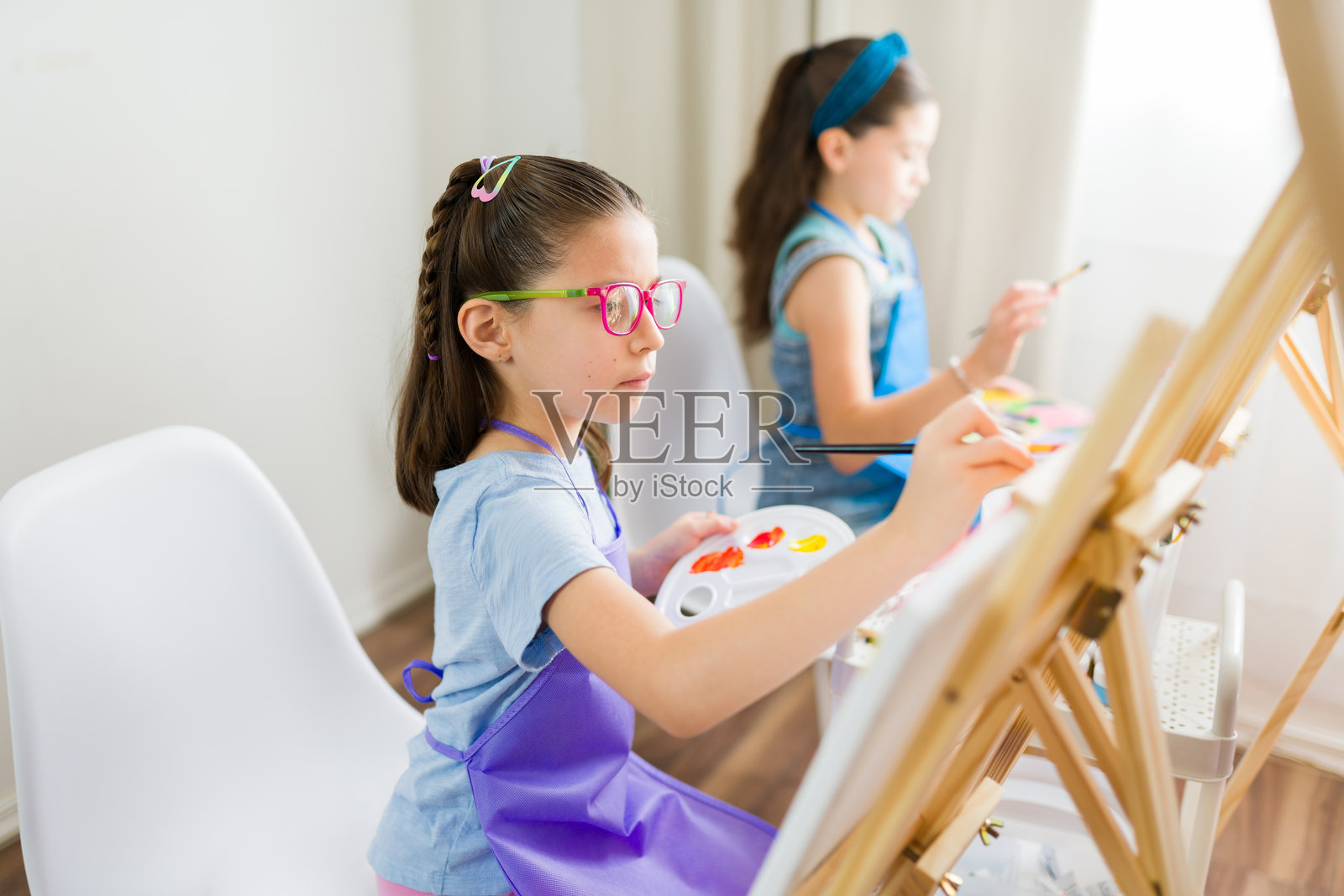 小学美术课：两名年轻学生在小画布上探索他们的创造力。照片摄影图片