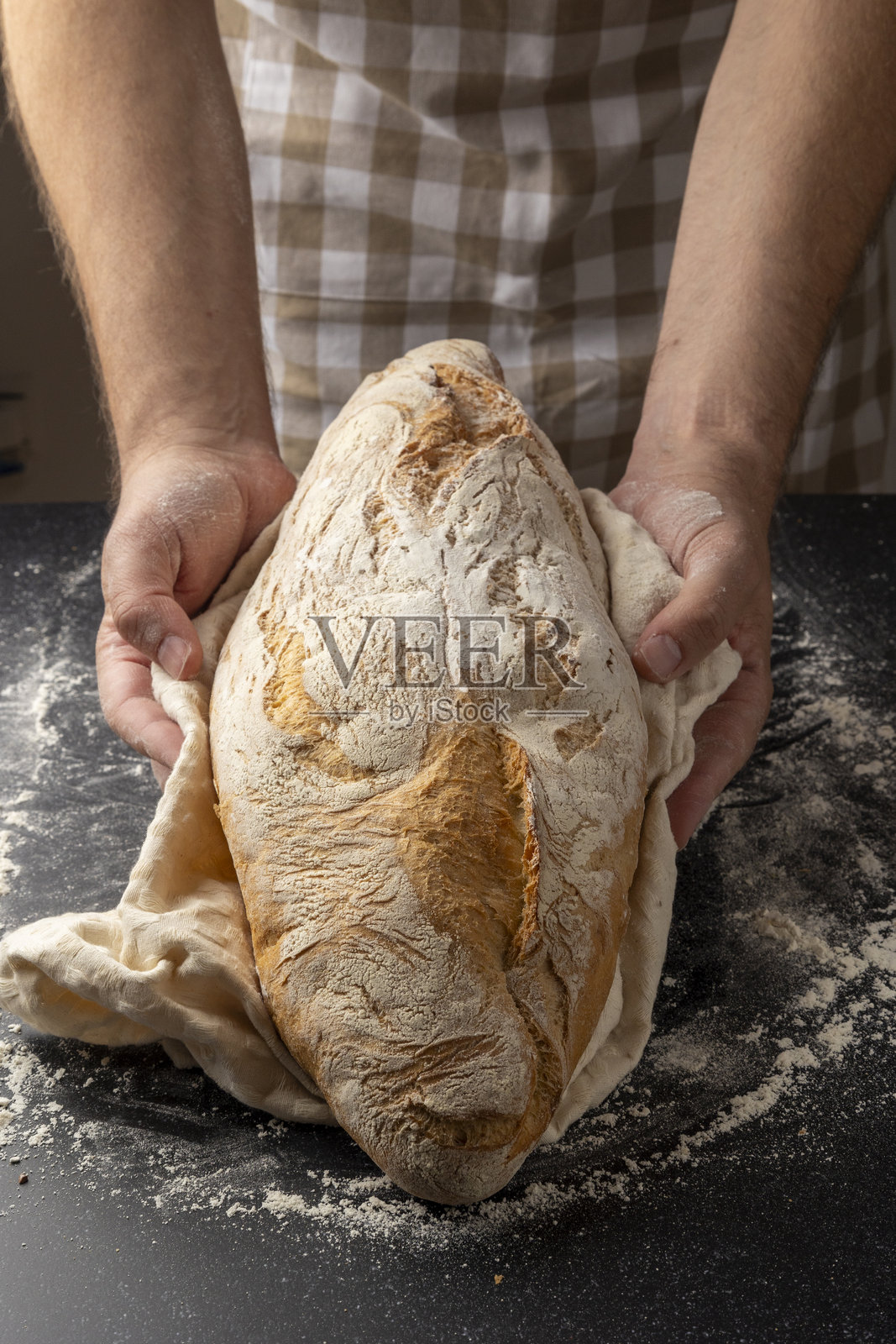 面包师傅手持撒满面粉的手工面包照片摄影图片