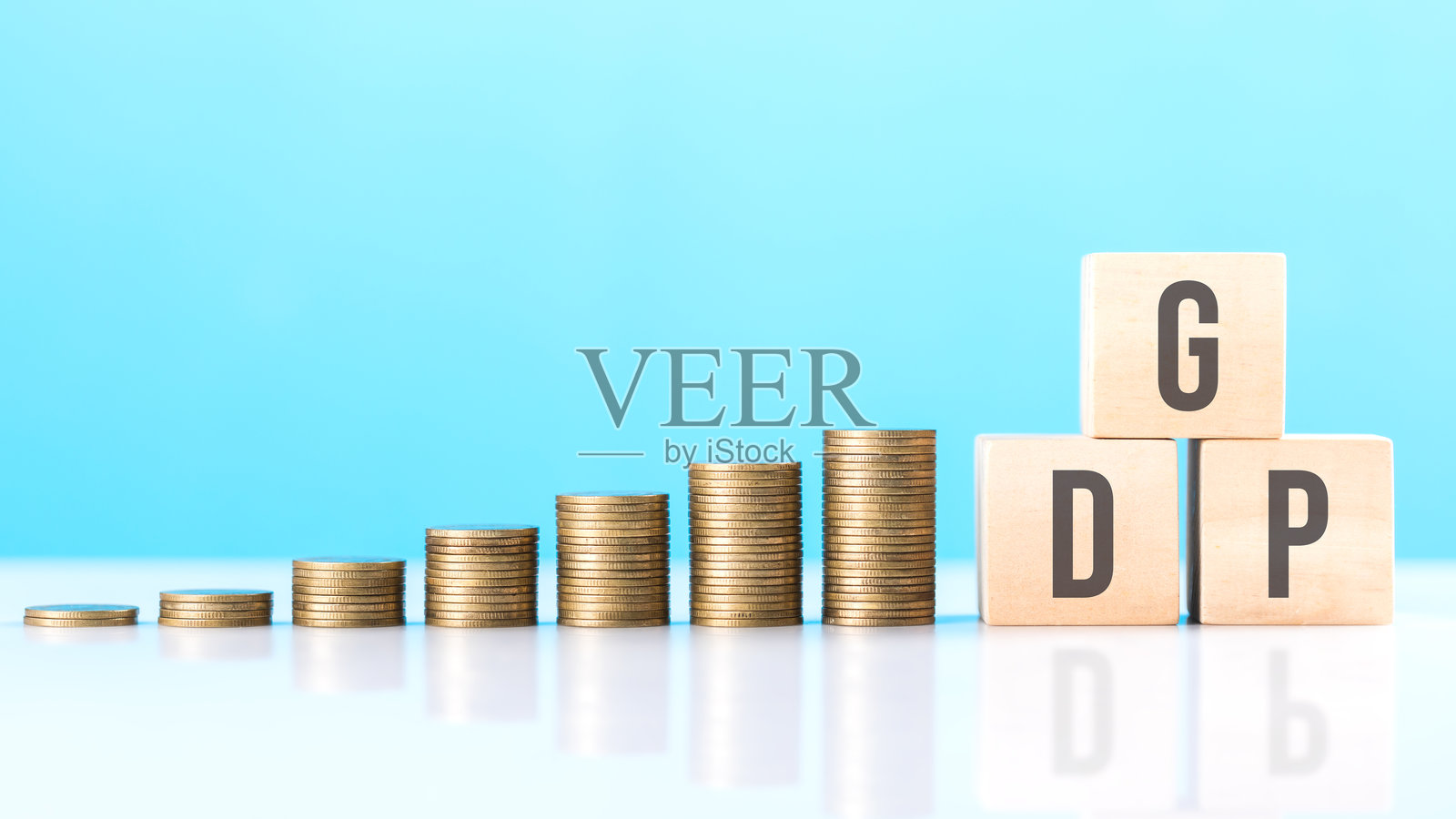 标有“GDP”的木块与一堆硬币并排放置。象征着经济增长，强调国内生产总值在评估财务进展和国家繁荣中的重要性。照片摄影图片