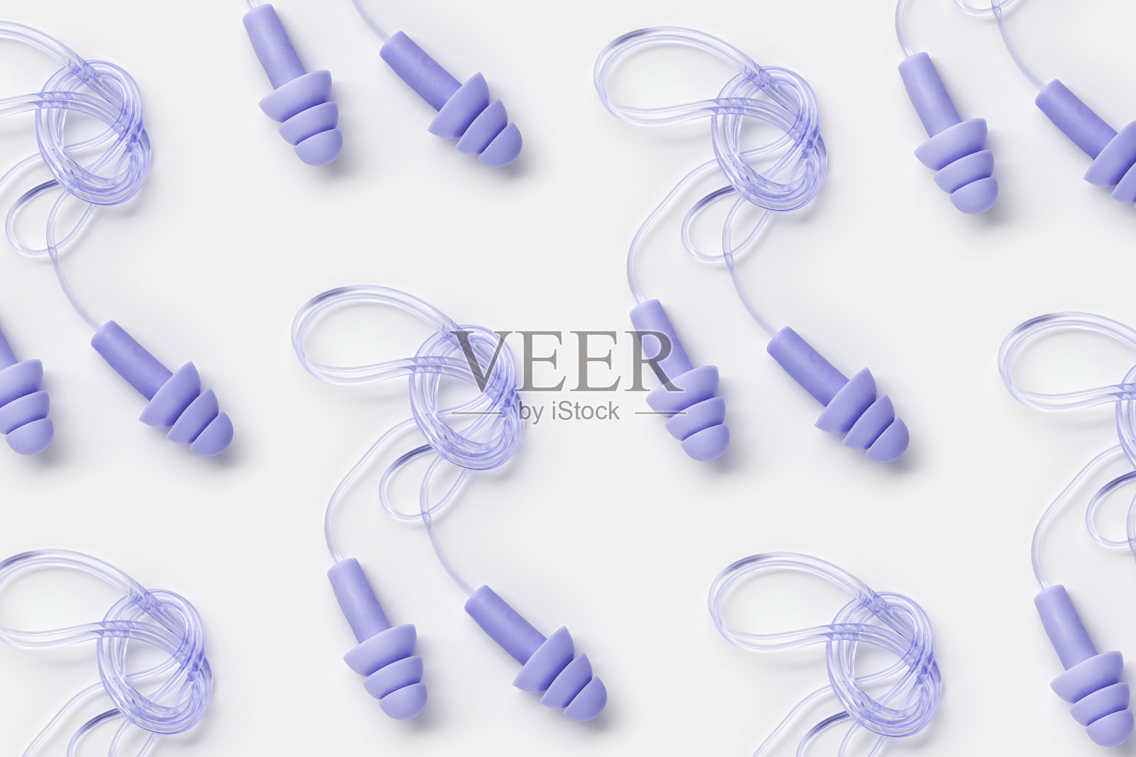 可重复使用的紫色硅胶耳塞，适用于游泳、睡眠和休息，背景为白色的极简风格图案。柔软、灵活的耳塞带有绳索，能有效隔绝噪音，保护听力，俯视图，平铺展示。照片摄影图片