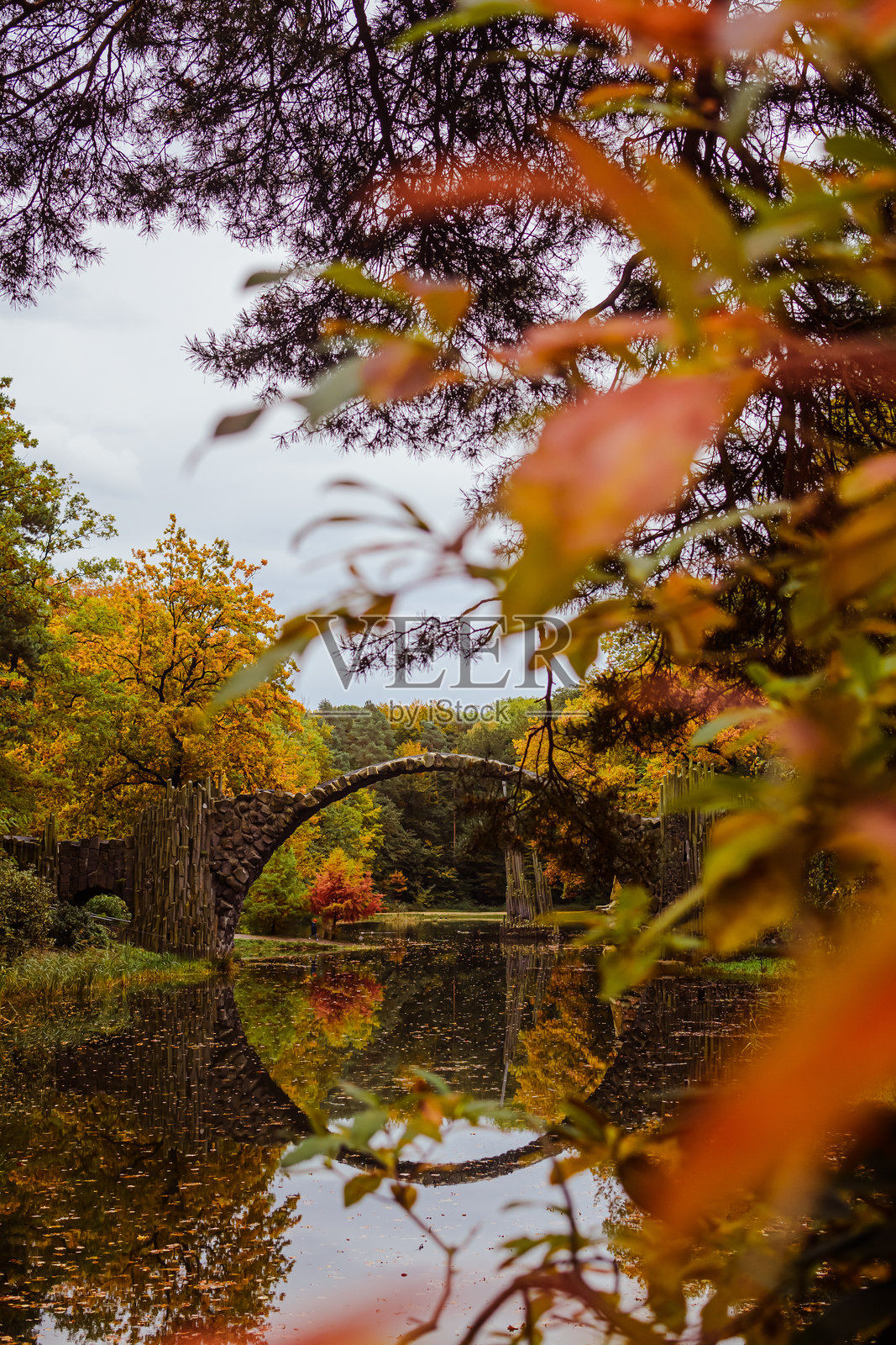 著名的拉科茨桥在水中的倒影，前景有黄色和橙色的树叶照片摄影图片