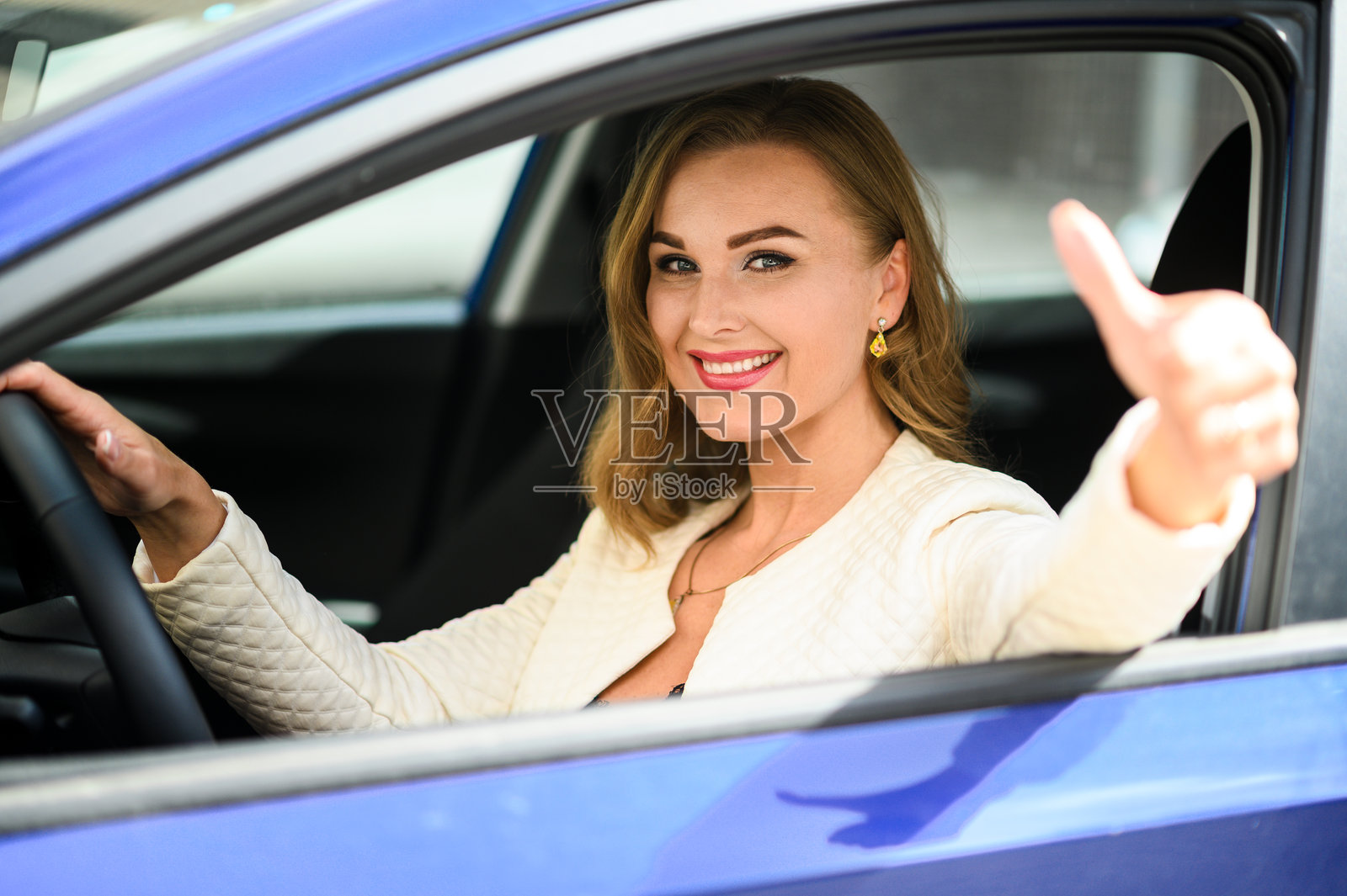快乐的女商人在开车时竖起大拇指。照片摄影图片