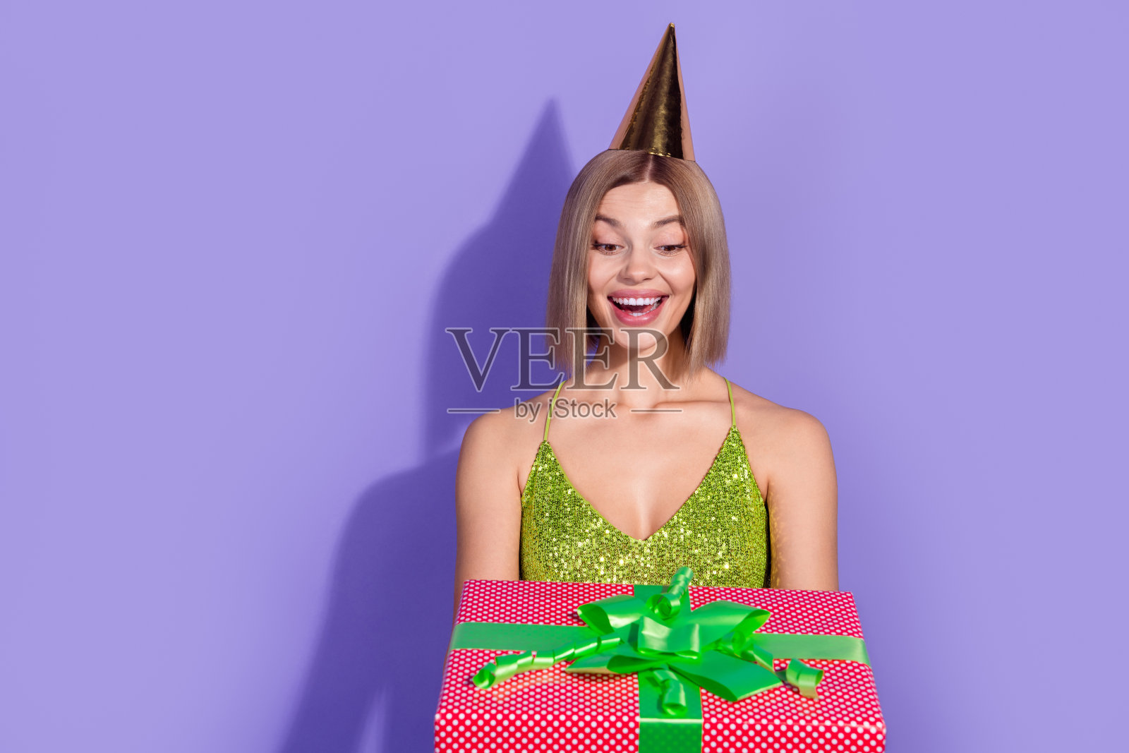 迷人可爱的女性穿着时尚服装，手持礼品盒，背景为紫色。照片摄影图片