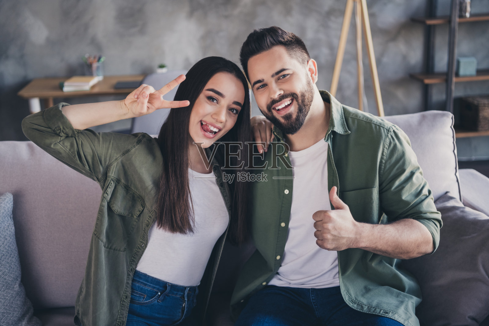 积极、快乐、充满爱的人们在现代阁楼公寓室内享受周末时光，竖起大拇指。照片摄影图片