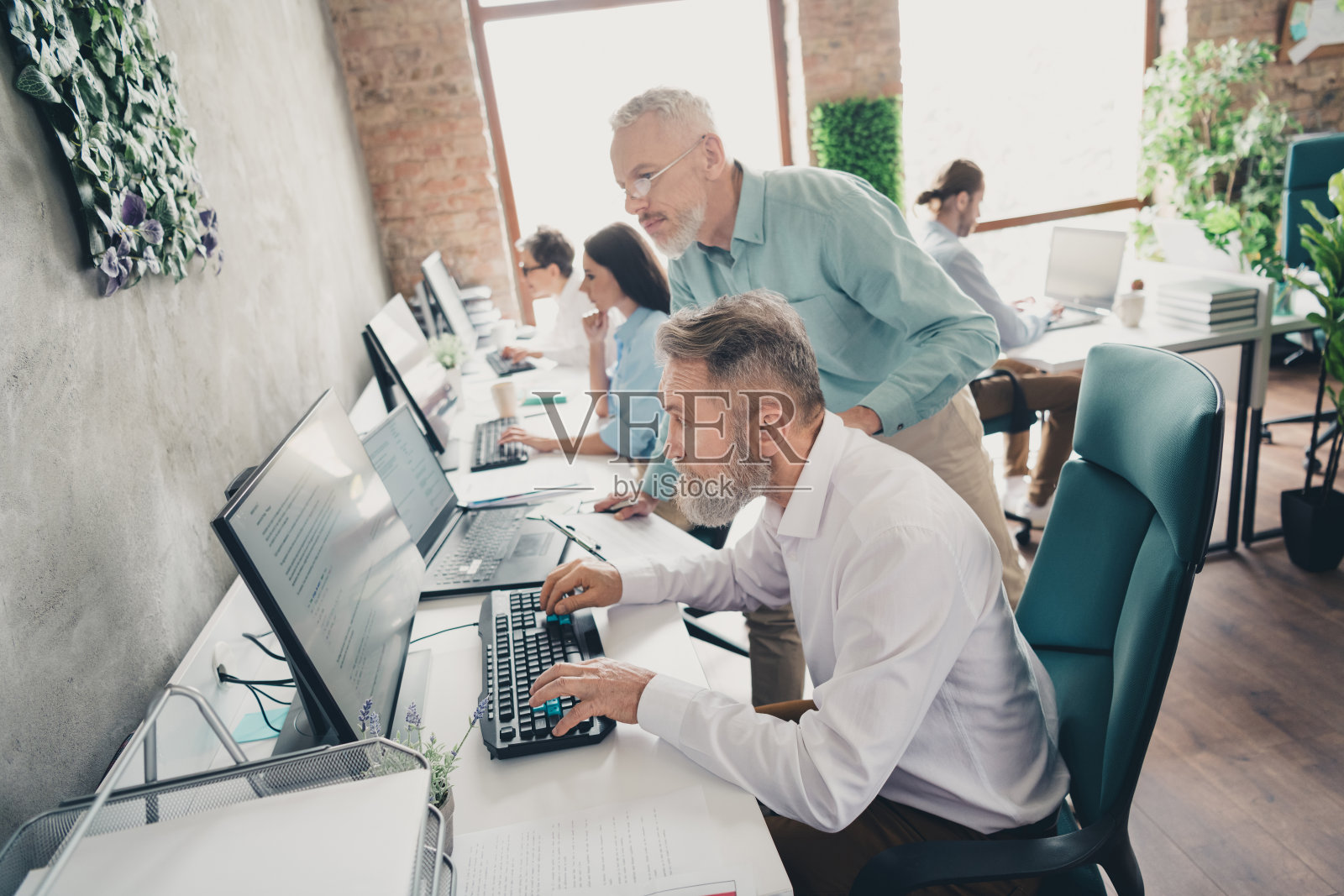 团队合作的初创公司伙伴们在舒适宜人的创意办公室阁楼内讨论项目。照片摄影图片