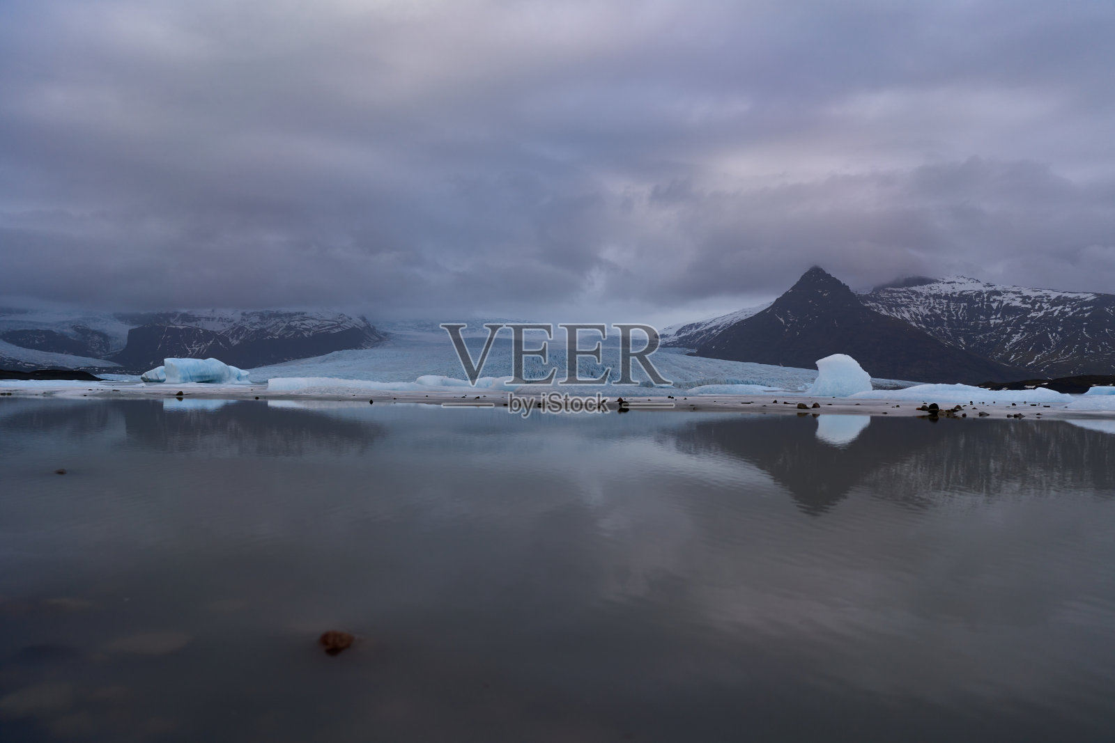 冰川湖在阴云密布的天空下映照在平静的水面上照片摄影图片