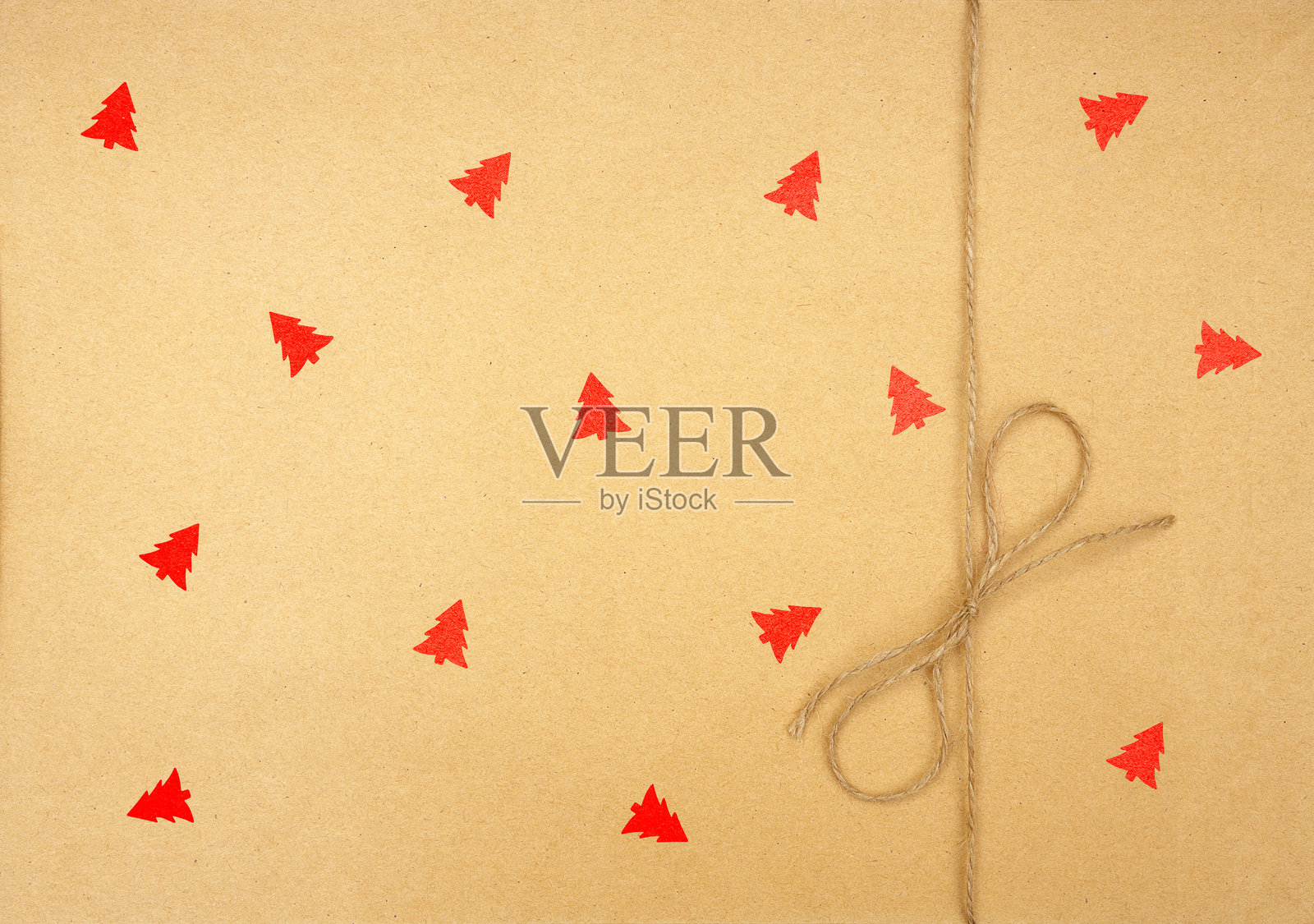 米色纸板表面上有小红色圣诞树图案和绑好的绳子照片摄影图片