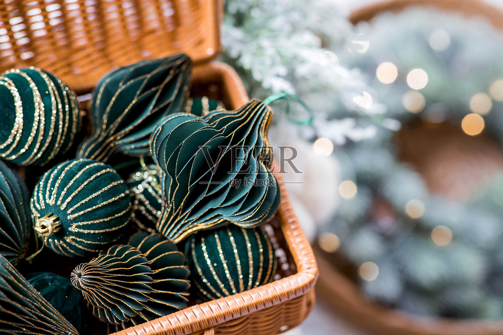 横幅。时尚的纸质和天鹅绒圣诞树饰品，采用斯堪的纳维亚风格，放在一个编织手提箱中。绿色调。2025年时尚新年和圣诞节的概念。照片摄影图片