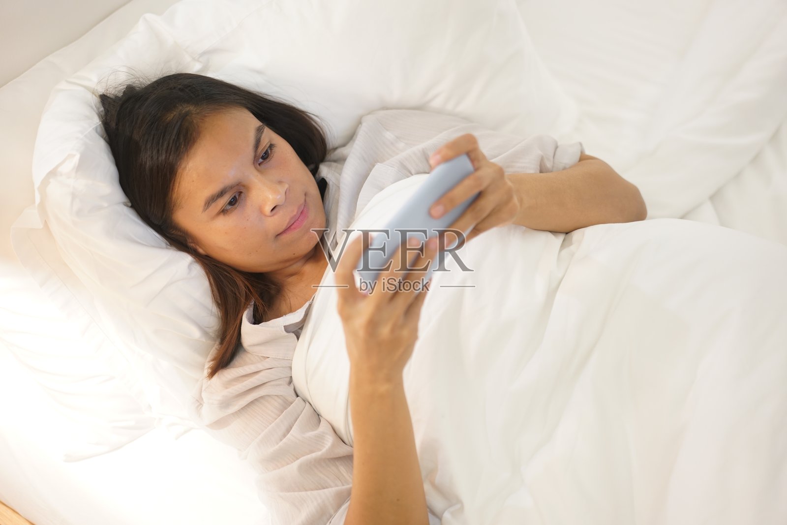 美丽快乐的年轻女性坐着微笑，手机在手，在线约会概念。照片摄影图片