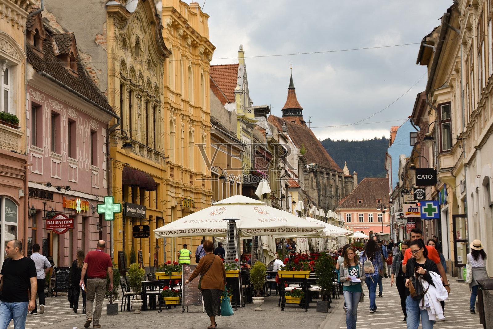 布拉索夫的鹅卵石街道上,游客众多,咖啡馆和色彩斑斓的建筑环绕。照片摄影图片