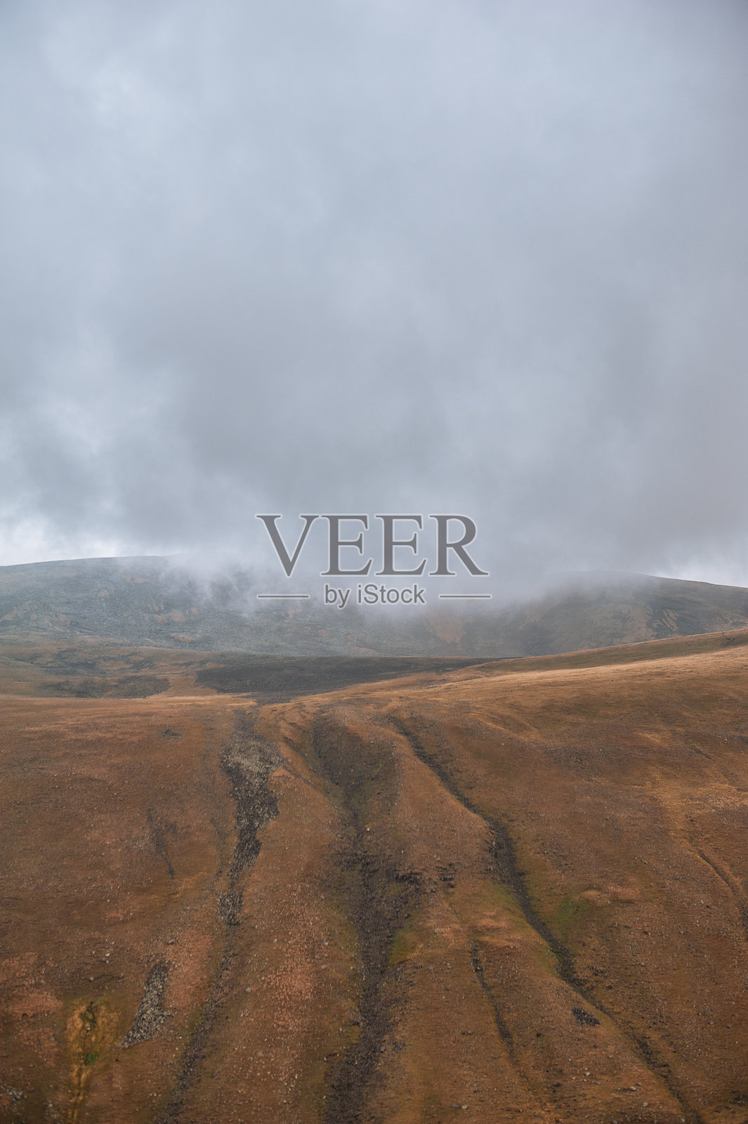 阴云密布的天空下，戏剧性的山谷与崎岖的地貌照片摄影图片