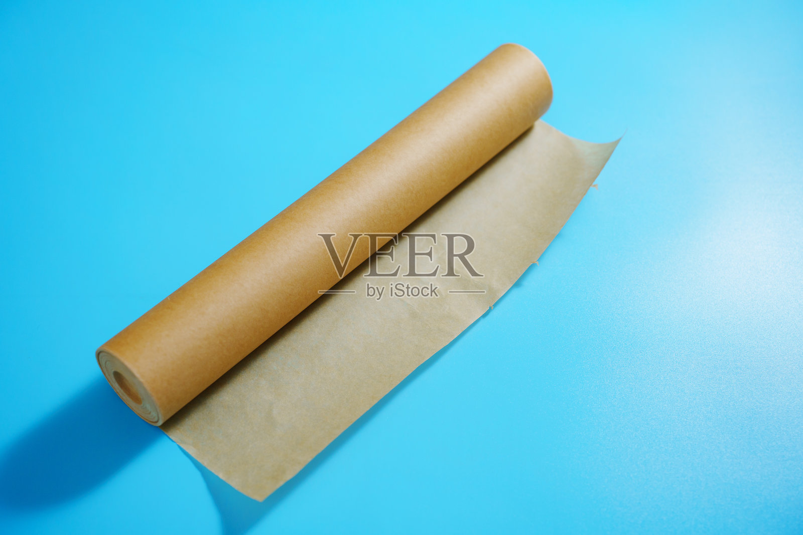 蓝色背景上的一卷烘焙纸。照片摄影图片