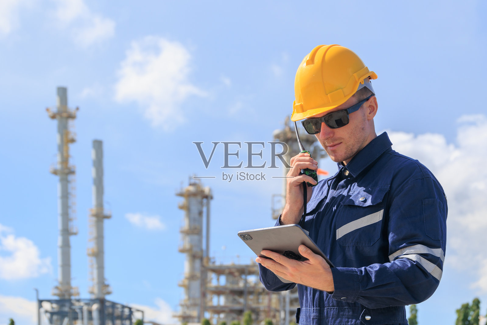 炼油厂石油工人在值班进行无线电控制操作。石油和天然气工业工程师在石化厂工作。照片摄影图片