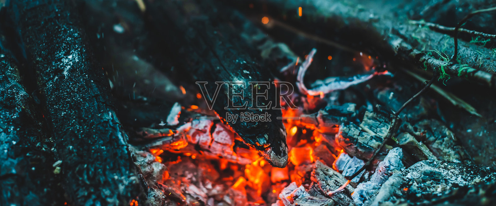 生动的炭火木材在火中燃烧的特写。温暖的背景氛围，营火的橙色火焰和蓝色烟雾。不可思议的全景篝火图像。美丽火焰中的燃烧木材。照片摄影图片