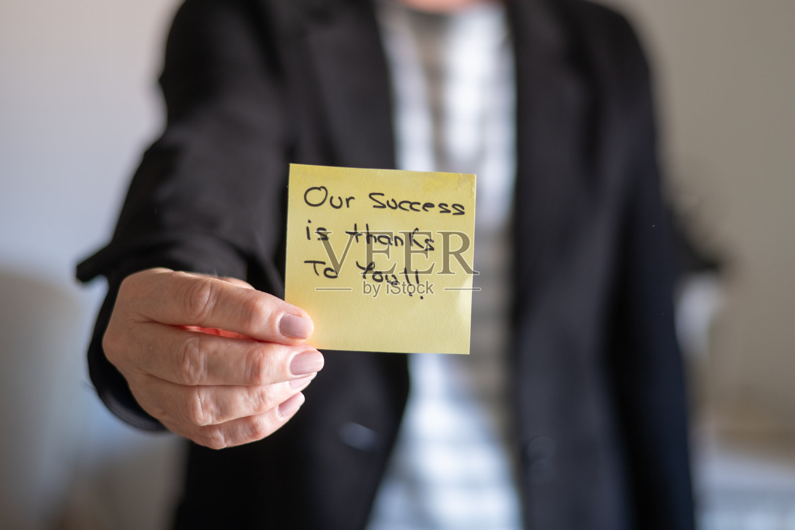 商务女性手持写有“我们的成功归功于您！”的便签。照片摄影图片