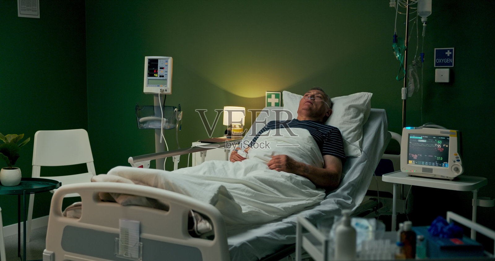 老年男子在医院休息，闭着眼睛，正在接受氧气支持以恢复肺炎。照片摄影图片