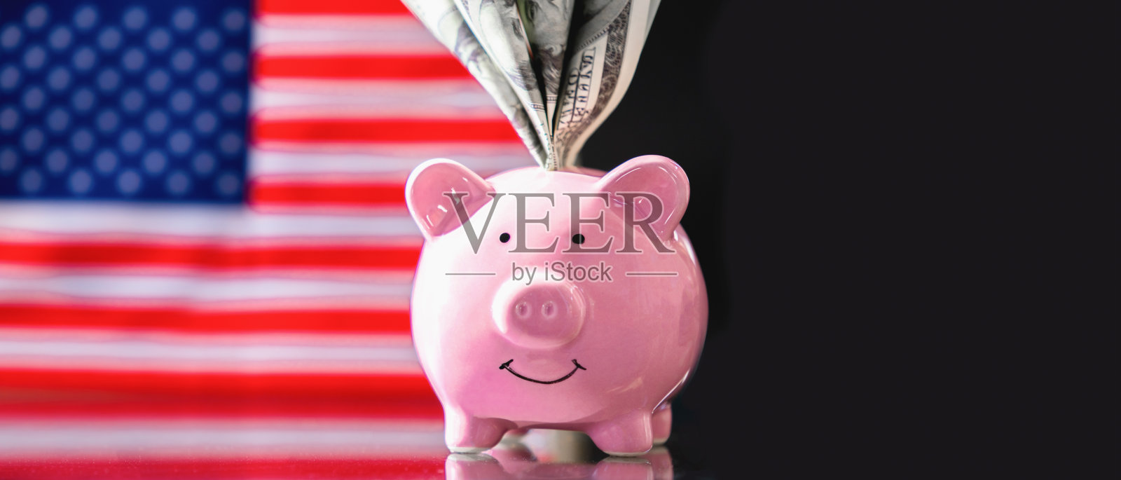 粉色猪储蓄罐与美国国旗上的美元钞票。留白空间。照片摄影图片