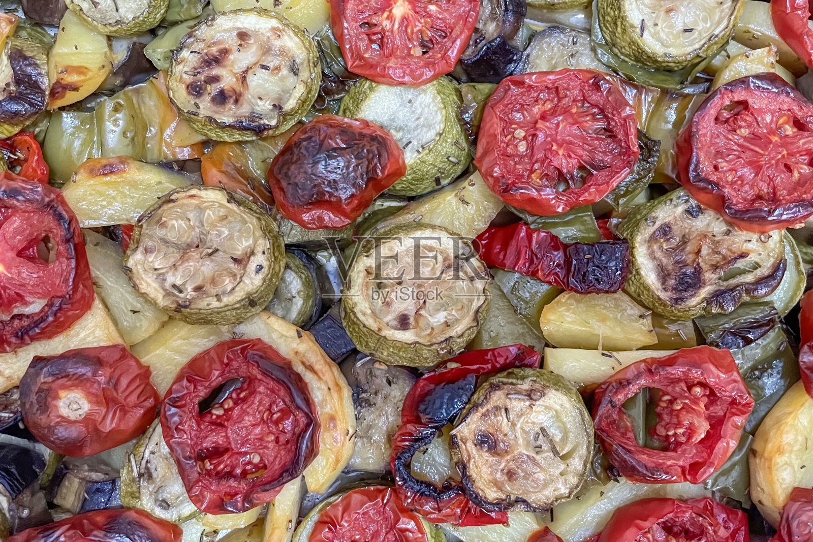 五彩缤纷的烤蔬菜托盘，包括土豆、 zucchini、茄子、西红柿和辣椒照片摄影图片