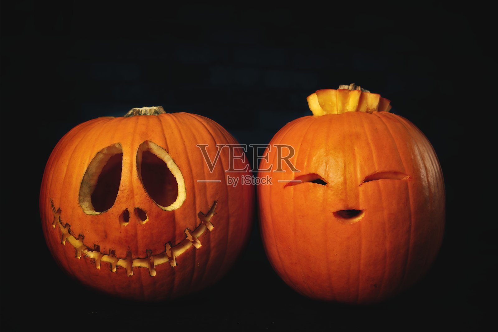 两个有趣的万圣节南瓜在黑色背景上。照片摄影图片