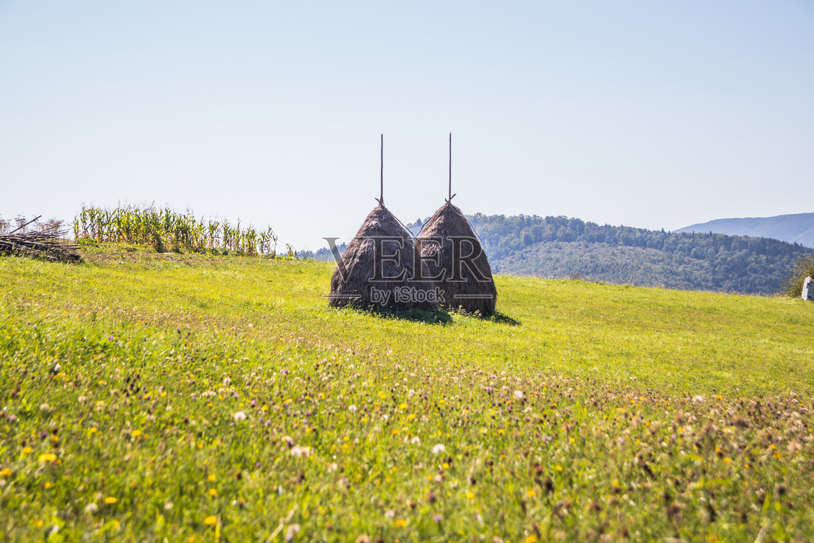 一幅如画的乡村风景，稻草堆点缀在雄伟的山脉和起伏的丘陵之间照片摄影图片