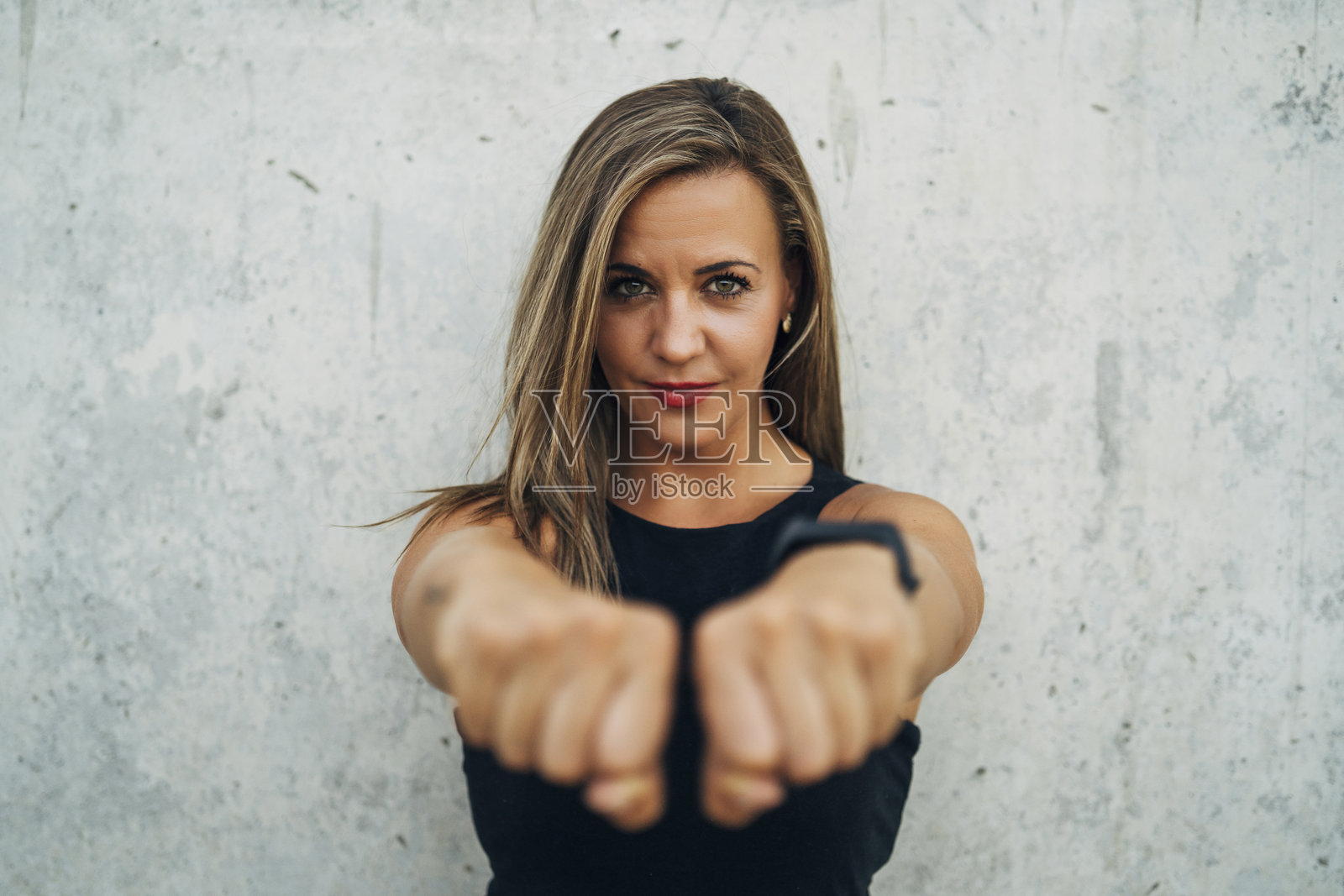 自信的女运动员在墙前握紧拳头照片摄影图片