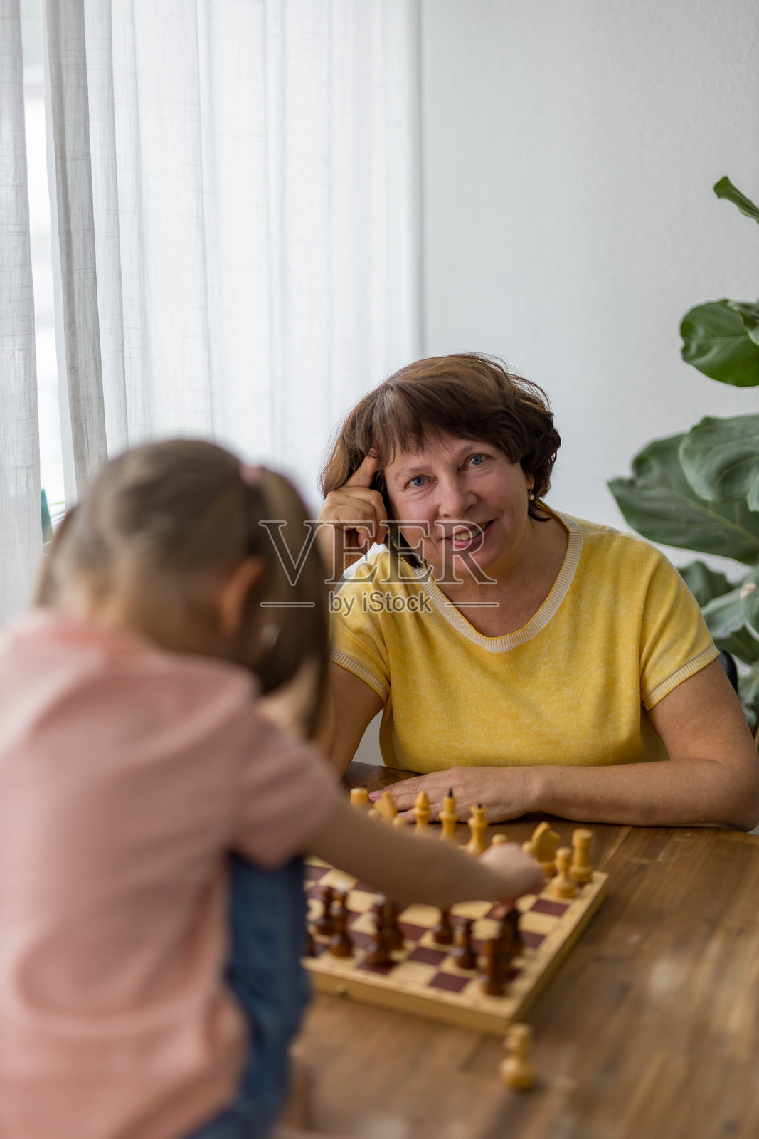 快乐的祖母和孙女一起下棋，共同创造珍贵的回忆照片摄影图片