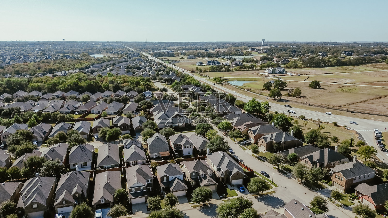 德克萨斯州巴顿维尔的农场到市场407号公路，沿着乡村郊区，适合发展大型规划社区、农场、牧场和带有瓦片屋顶的两层住宅，绿树成荫，航拍视角。照片摄影图片