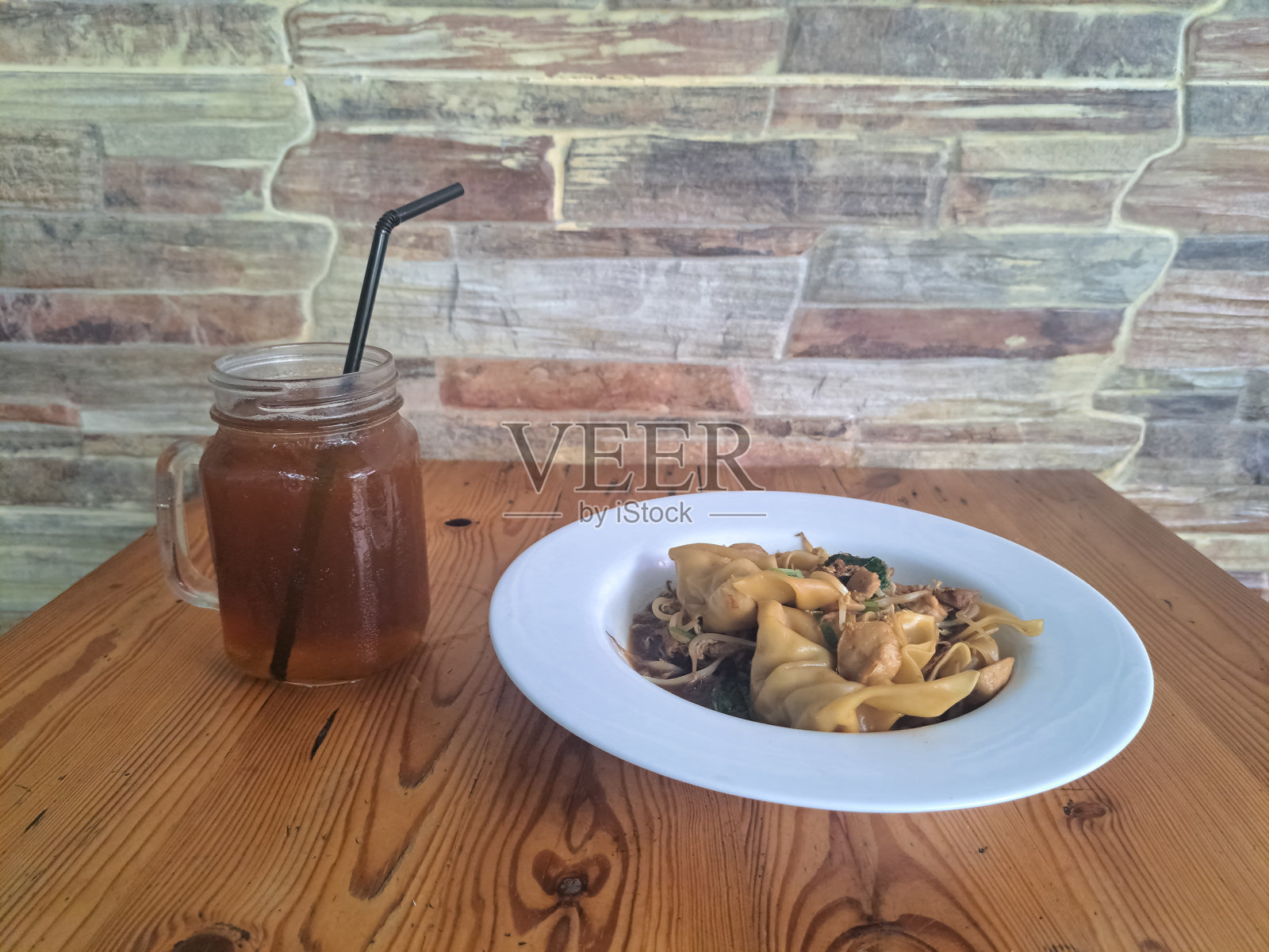 美味的鸡肉饺子是用鸡肉、鸡蛋、肉丸和蔬菜以及东方香料制作的。新鲜的冰茶或玻璃杯中的冰茶。食品和饮料菜单。照片摄影图片
