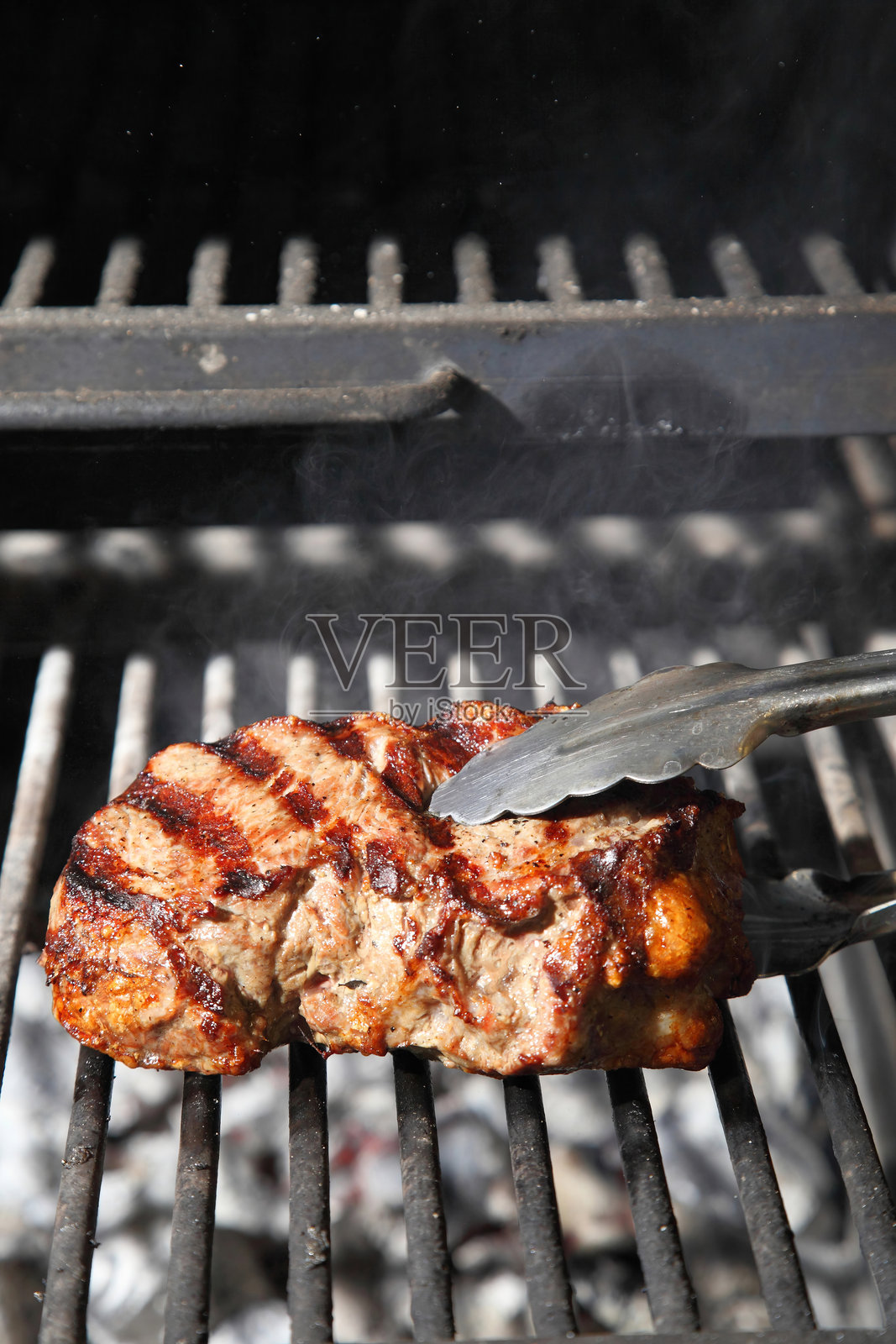 在烤架和炭火上烹饪牛排。在餐厅里烤牛排。照片摄影图片