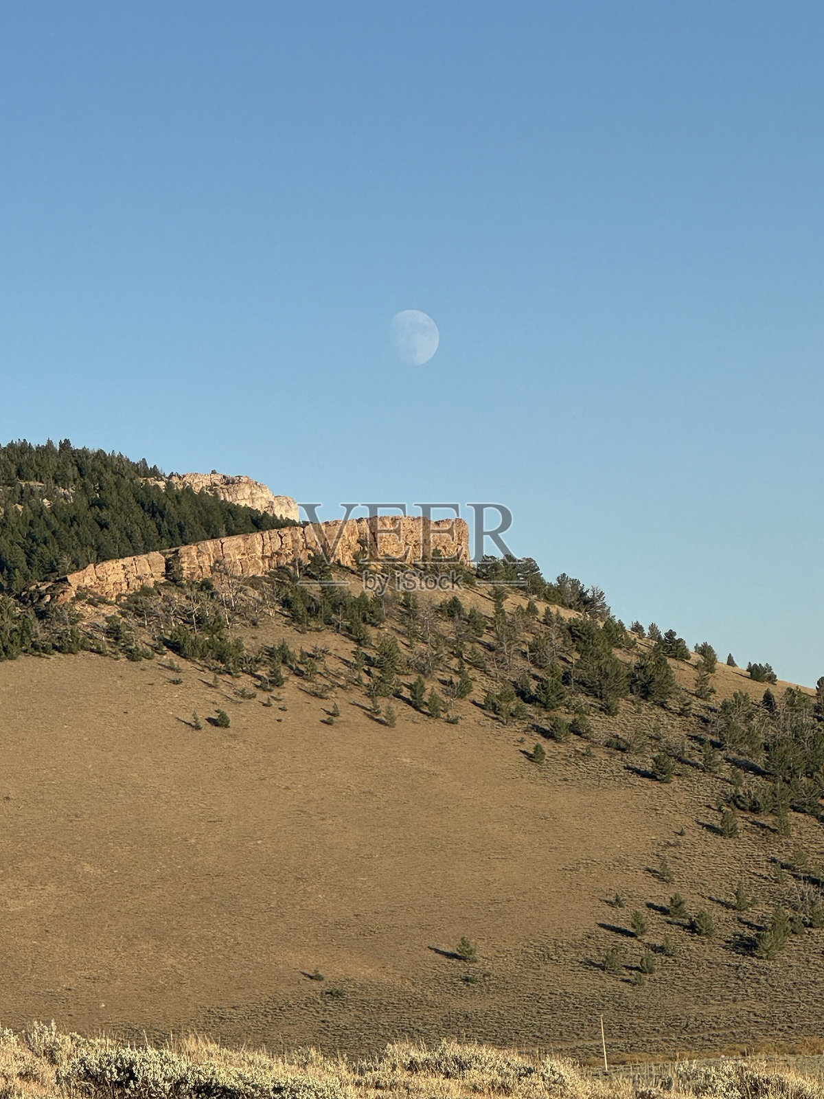 白天的月光下，荒凉的山丘和岩石山脊照片摄影图片