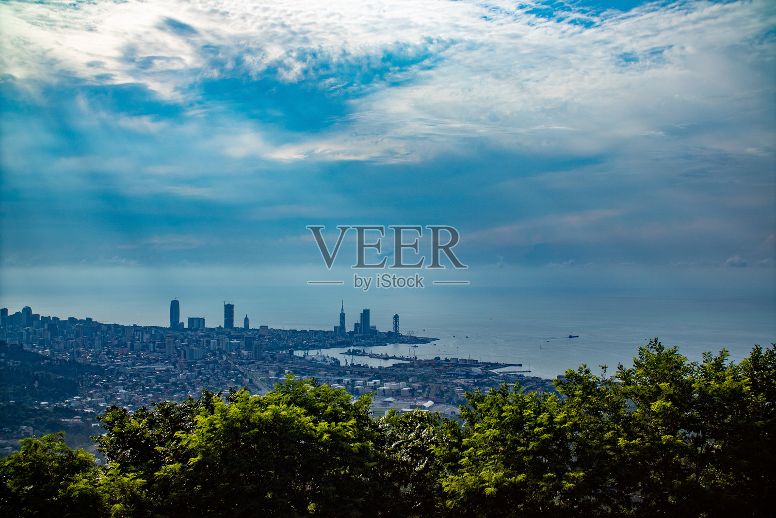 从树木环绕的山顶俯瞰繁忙城市的美丽景色照片摄影图片