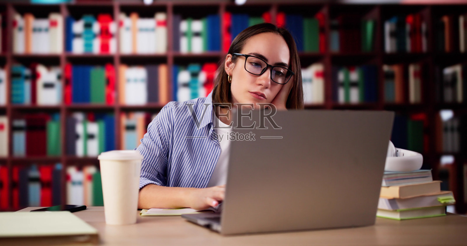 疲惫的大学生在图书馆里照片摄影图片