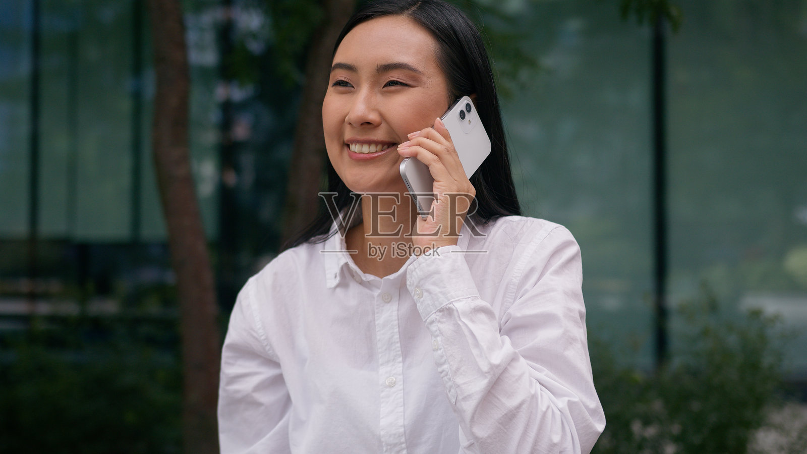 兴奋的亚洲韩国女商人微笑着用手机通话，享受成功的喜悦，作为经理达成职业协议，收获好消息，惊讶于城市户外的科技。照片摄影图片