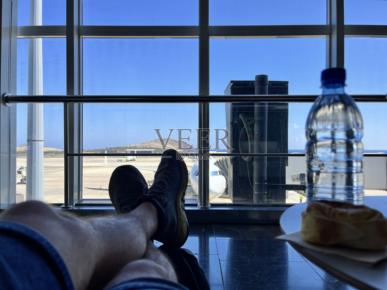 背包客男性在出发机场区域休息，吃零食，放松心情，等待他的航班前往西班牙大加那利岛的拉斯帕尔马斯/马斯帕洛马斯开始假期。照片摄影图片