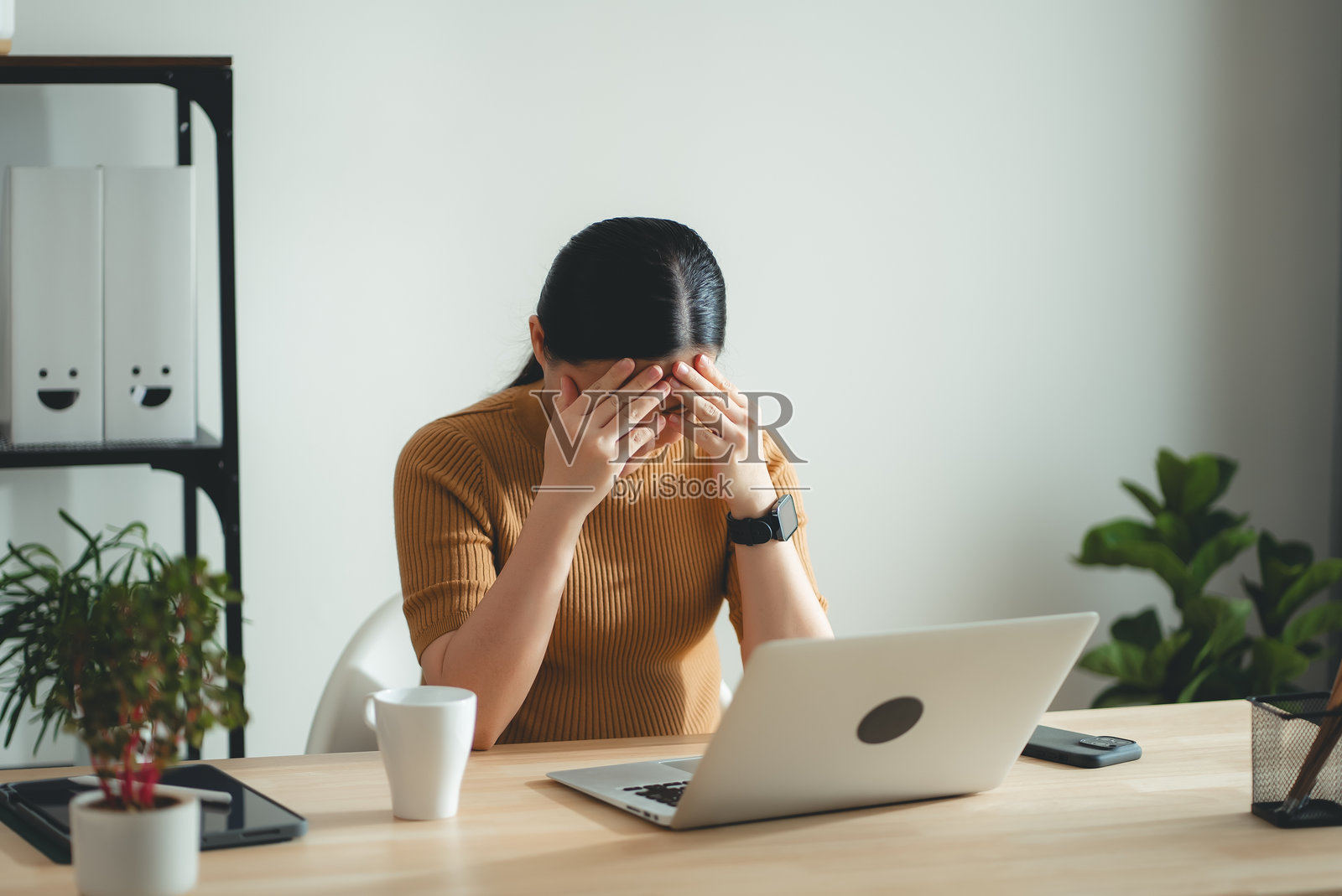 亚洲孕妇坐在家庭办公室，担心地思考工作。照片摄影图片