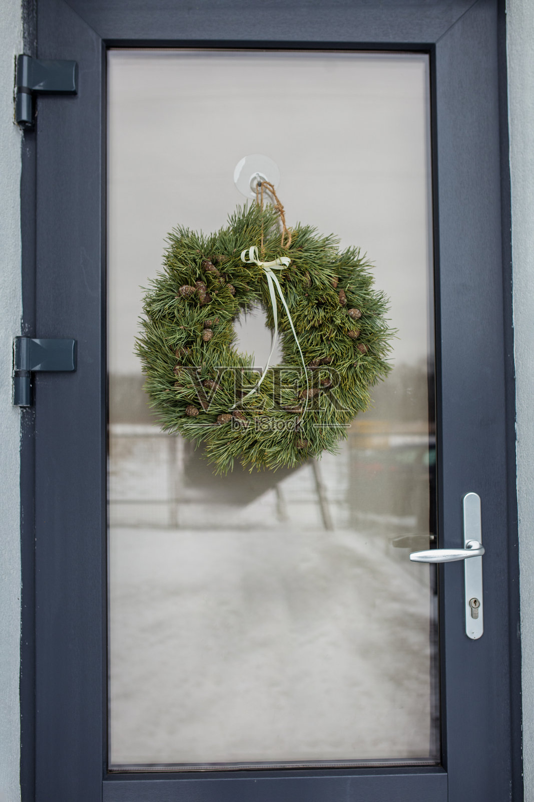 绿色松树花环装饰着松果，挂在冬季的深色前门上。圣诞节。照片摄影图片